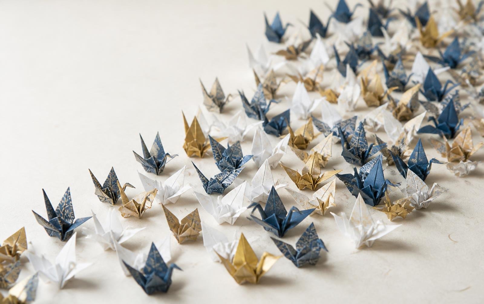 Centenas de tsurus de papel dobrados à mão em tons de branco, índigo e dourado